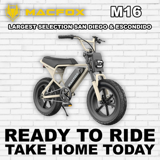 Macfox M16 eBike in desert beige color, side view, parked on rugged terrain with a rocky background