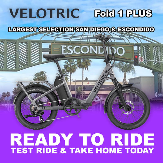 Velotric Fold 1 PLUS eBike in Stone Gray, folded and ready to ride, product image on a plain background.