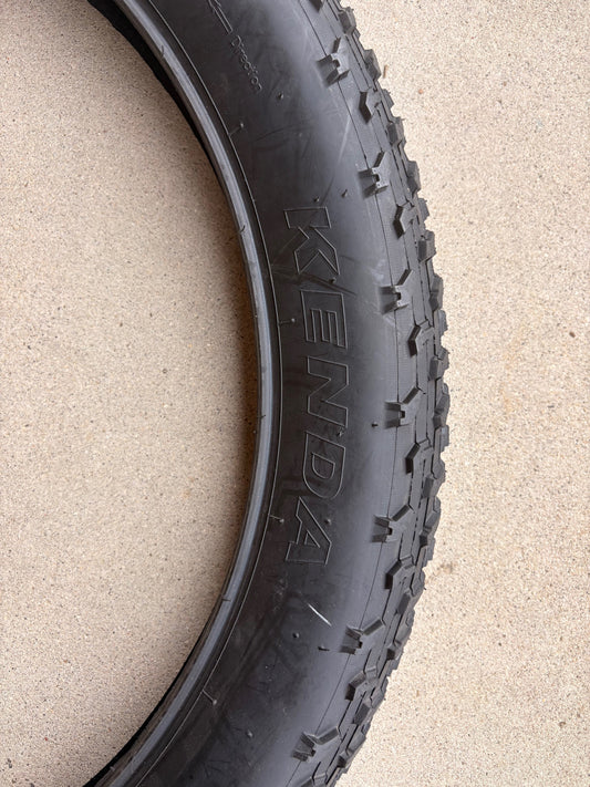 A black eBike with 26x4 inch Kenda Krusade fat tires, shown in a side profile against a white background.