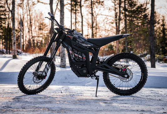 Side view of the eMOTO Talaria Sting MX3 electric dirt bike in black and yellow, showcasing its frame, wheels, and suspension system against a white background.