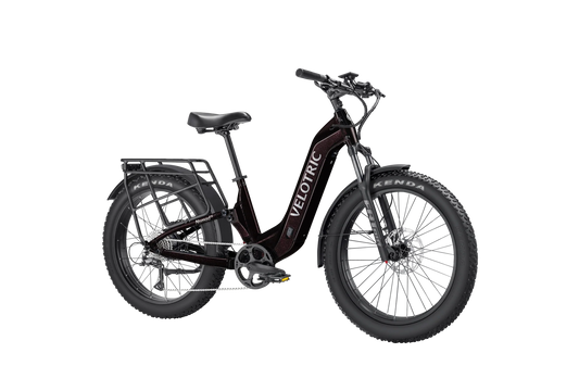 Side view of the Velotric Nomad 2X eBike in matte black, showing its fat tires, front suspension fork, integrated battery, and rear cargo rack.